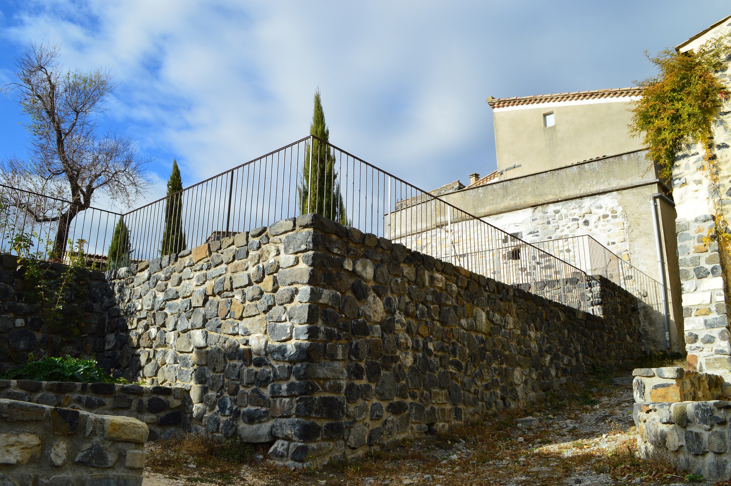 Parement en pierres de basalte devant un mur de soutènement en BA. Aménagement d'une place publique à Saint Pons